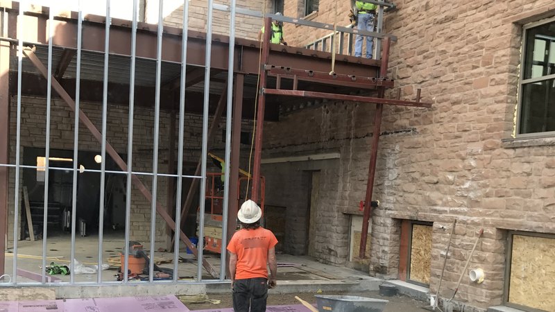 Hanging structural steel from the telehandler at the Meeker Courthouse remodel, beside the existing stone building