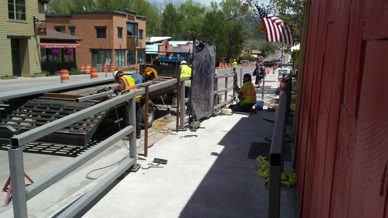 Crew installing steel guardrail along a downtown street project
